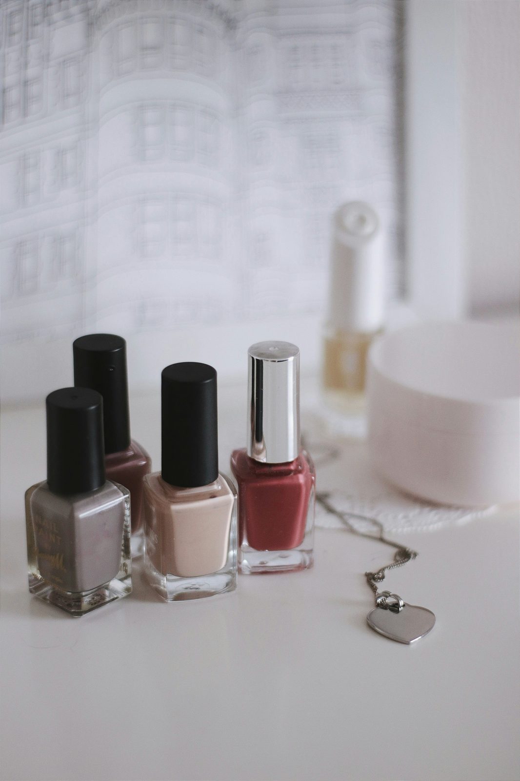 Flesjes nagellak in nude en roze tinten op een witte tafel