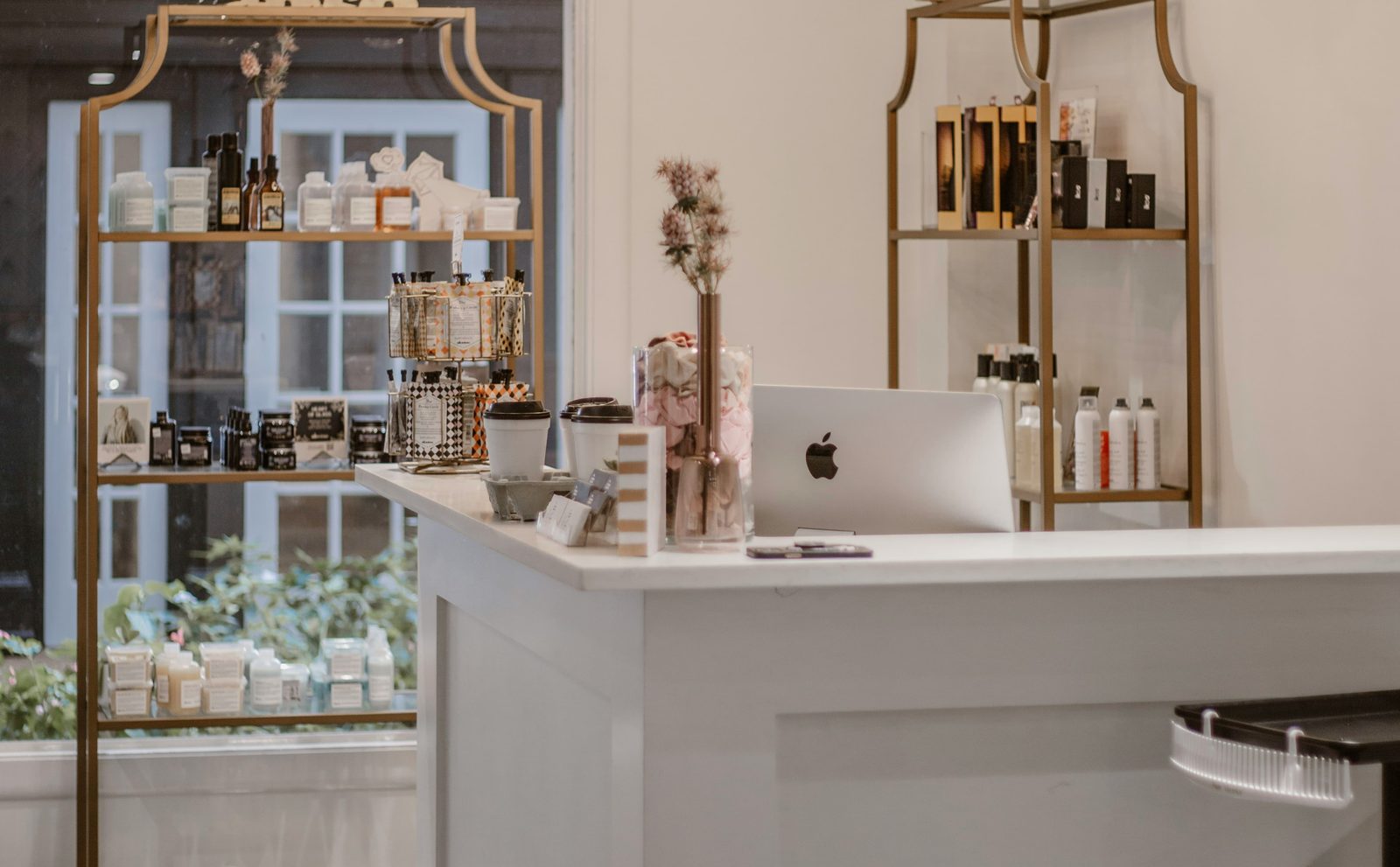 Lichte, stijlvolle schoonheidssalon met een witte balie en producten op gouden schappen