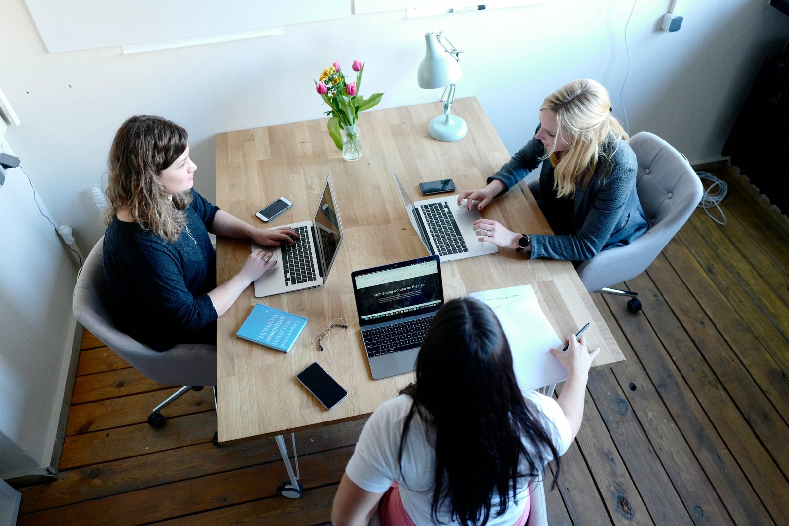Drie beauty-professionals werken samen aan een tafel met laptops